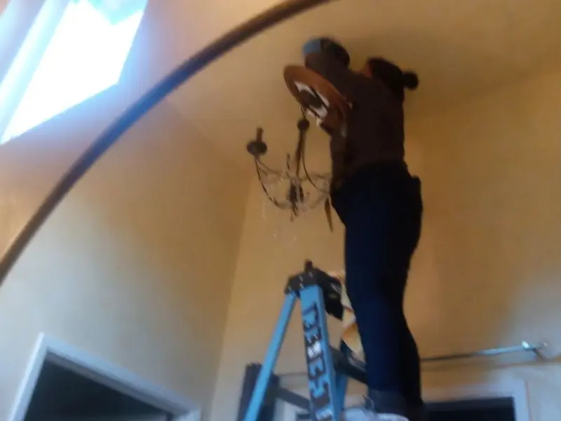 Electrician installing a chandelier in a Four Bridges residence